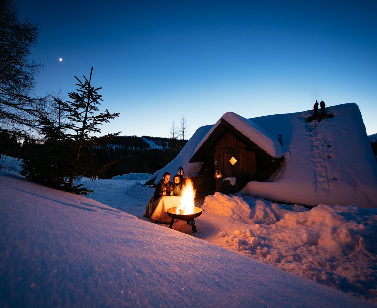 Zwei Personen sitzen vor Lagerfeuer am Abend auf der Anderlehütte in Kärnten | © Urlaub am Bauernhof Kärnten / Daniel Gollner