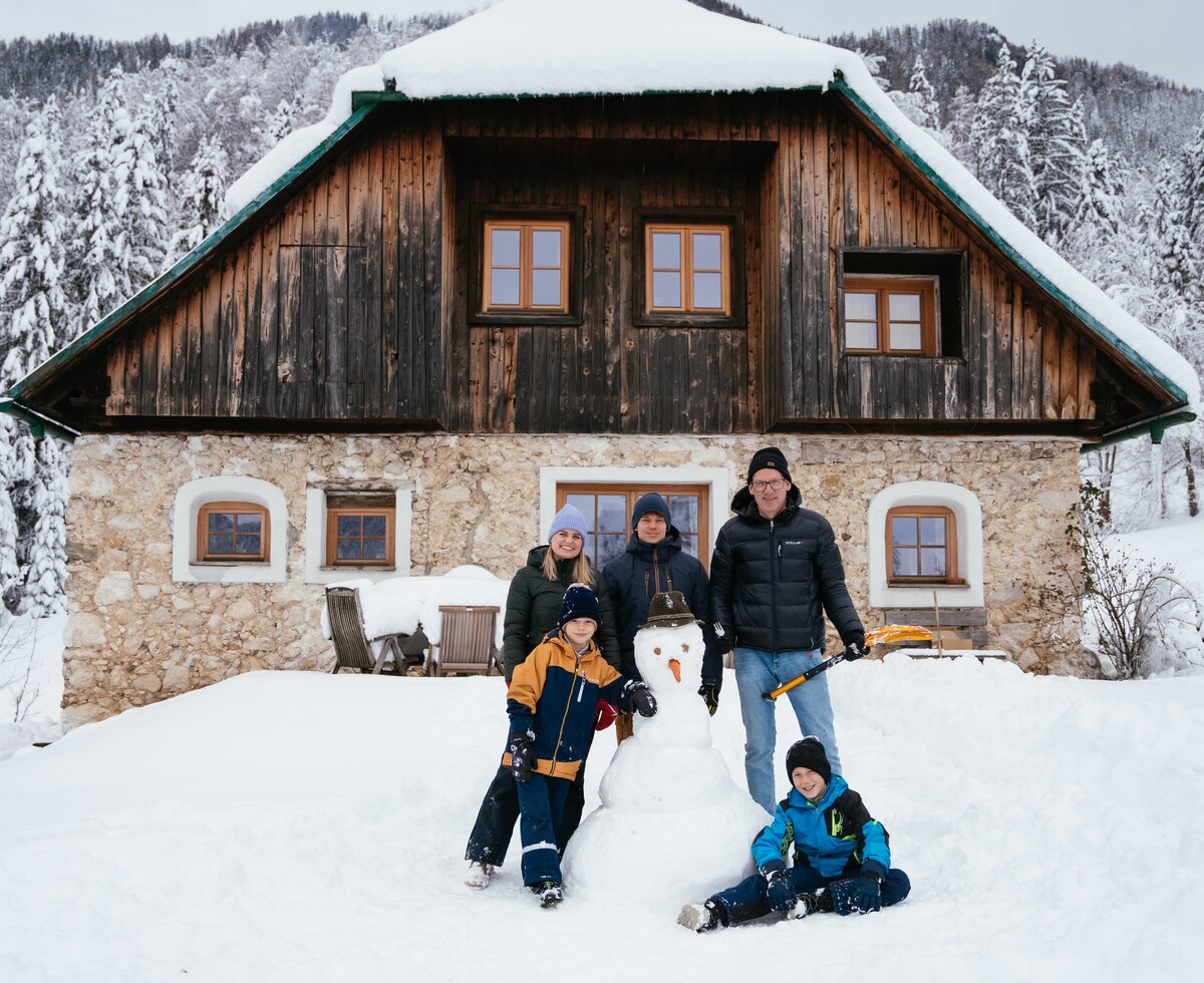 Familie steht bei Schneemann vor Hütte | © Daniel Gollner / Urlaub am Bauernhof Kärnten