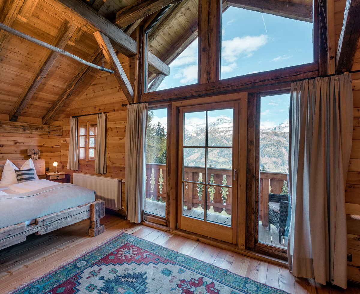 Schlafzimmer mit Holzbett und Aussicht auf die Berge einer Premiumhütte | © Günter Standl 