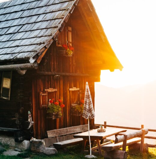 Die Almhütte scheint im Morgenlicht bei der aufgehenden Sonne in Kärnten | © Urlaub am Bauernhof Kärnten / Daniel Gollner