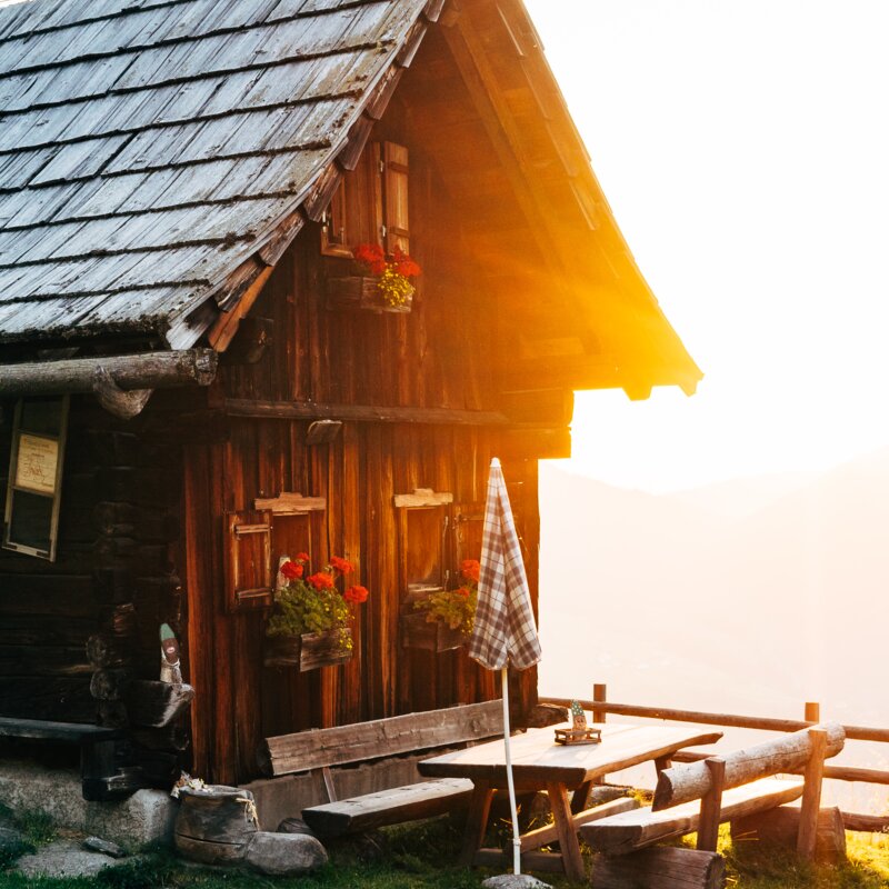 Die Almhütte scheint im Morgenlicht bei der aufgehenden Sonne in Kärnten | © Urlaub am Bauernhof Kärnten / Daniel Gollner