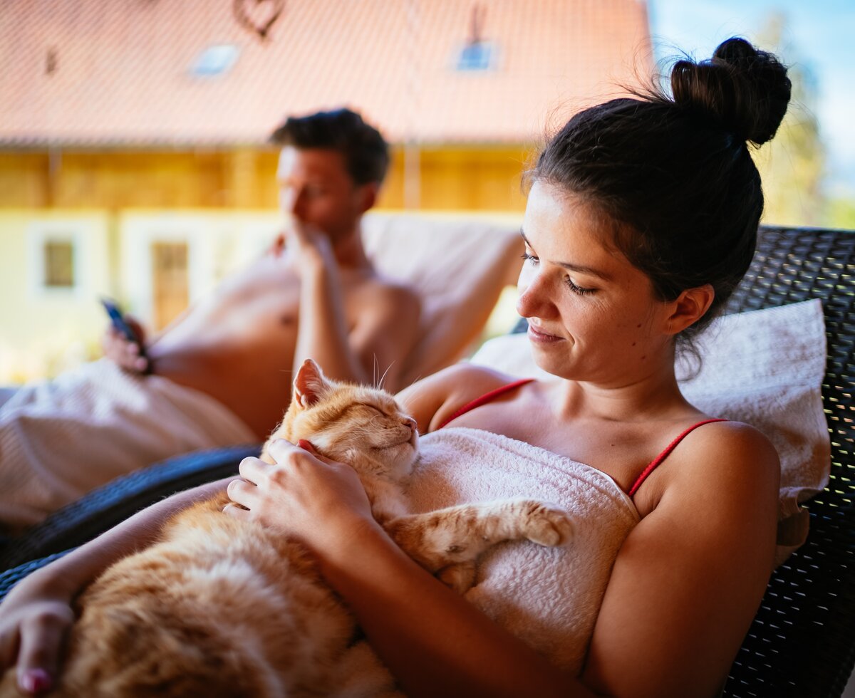 Paar relaxed mit der Katze vor der Sauna | © Urlaub am Bauernhof / Daniel Gollner