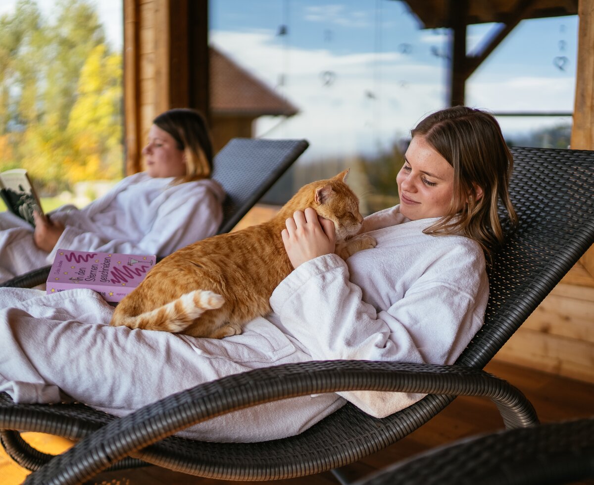 Urlauberin streichelt Katze im Liegestuhl | © Urlaub am Bauernhof / Daniel Gollner