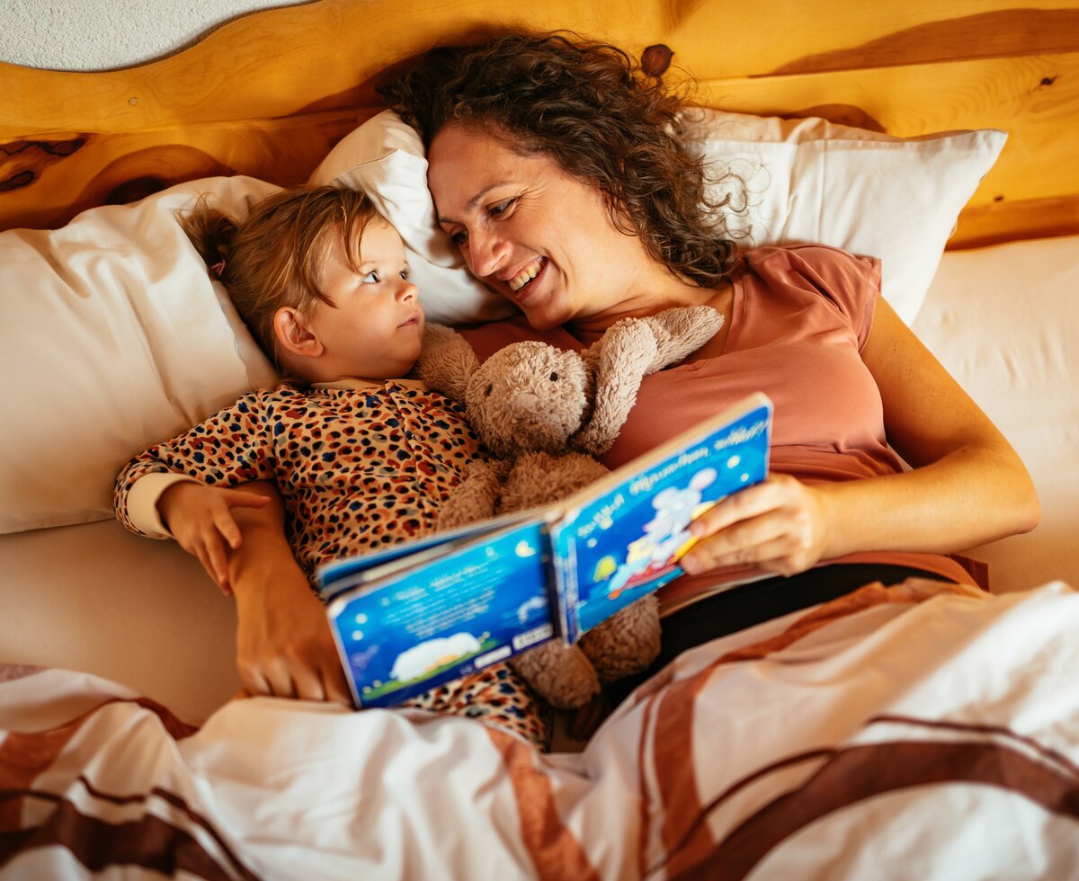 Frau und kind liegen im Bett und lesen gemeinsam ein Buch | © Urlaub am Bauernhof / Daniel Gollner