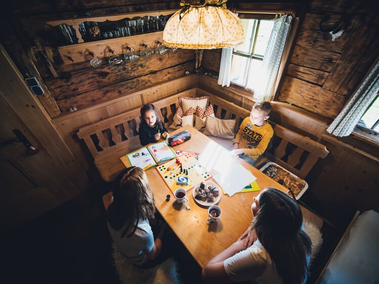 Familie sitzt am Hüttentisch und spielt Mensch ärger dich nicht | © Urlaub am Bauernhof Salzburg / Daniel Gollner 