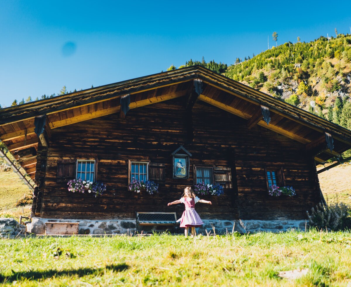 Kind dreht sich vor der Astenhütte im Dirndl  | © Urlaub am Bauernhof Salzburg / Daniel Gollner 