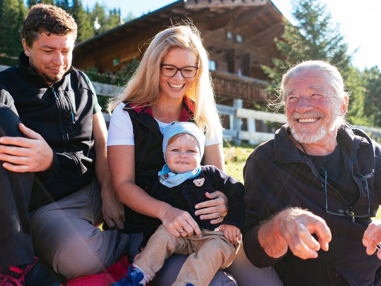 Familie sitzt vor der Hütte im Gras und picknickt  | © Urlaub am Bauernhof Tirol / Daniel Gollner 