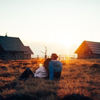 Pärchen sitzt auf der Wiese und genießt den Sonnenunterang | © Urlaub am Bauernhof Kärnten / Daniel Gollner