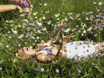 Frau liegt in der Blumenwiese | © Urlaub am Bauernhof Kärnten / Eisenberger