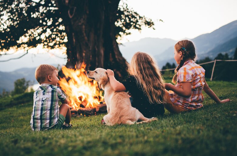 Kinder sitzen mit dem Hund beim Lagerfeuer | © Urlaub am Bauernhof Kärnten/ Daniel Gollner