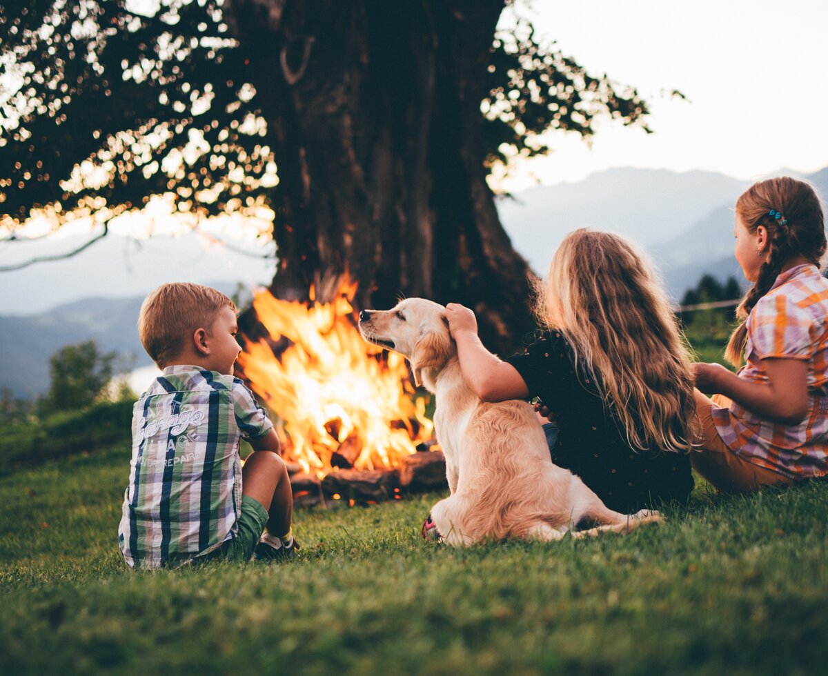 Kinder sitzen mit dem Hund beim Lagerfeuer | © Urlaub am Bauernhof Kärnten/ Daniel Gollner