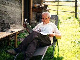 Mann liest Zeitung im Liegestuhl | © Urlaub am Bauernhof Kärnten / Daniel Gollner