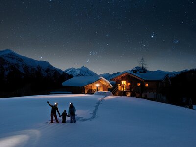 Familie blickt auf Sternenhimmel mit Hütte im Hintergrund  | © Klaus Dapra