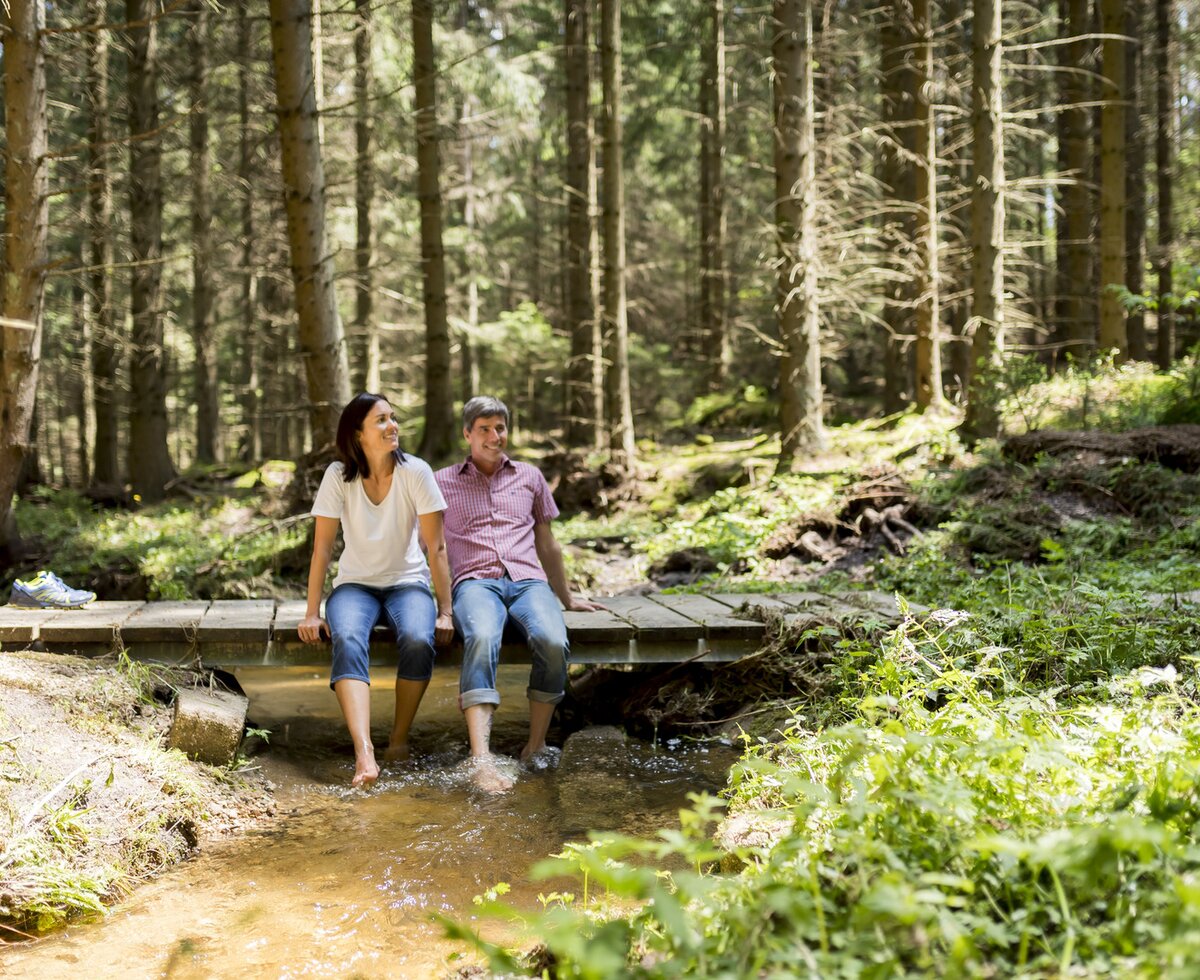 Couple sitting on bridge with feet hanging in stream | © Waldviertel Tourismus / Robert Herbst