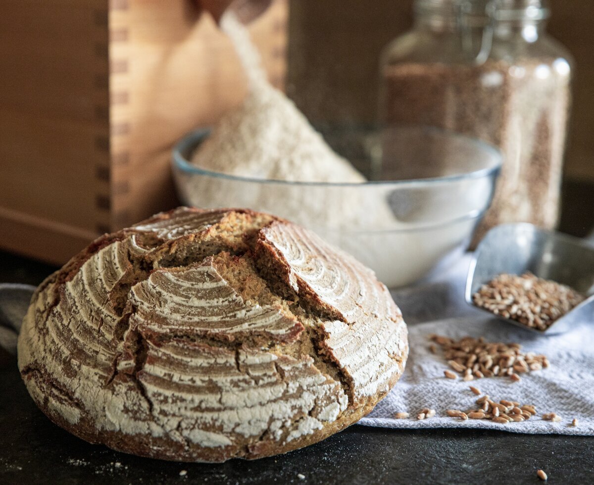 Ein Laib frisch gebackenes Brot, eine Getreidemühle und Getreidekörner | © Urlaub am Bauernhof Oberösterreich / Puremotions Photography