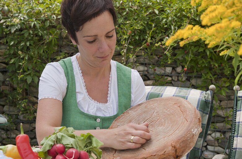 Bäuerin macht ein Kreuzzeichnung zur Segnung eines Laibes Brot | © Urlaub am Bauernhof Oberösterreich / Uli Matscheko