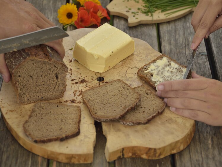 Brotscheiben werden mit Butter bestrichen und mit Kräutern verziert | © Urlaub am Bauernhof Oberösterreich / Ralph Fischbacher