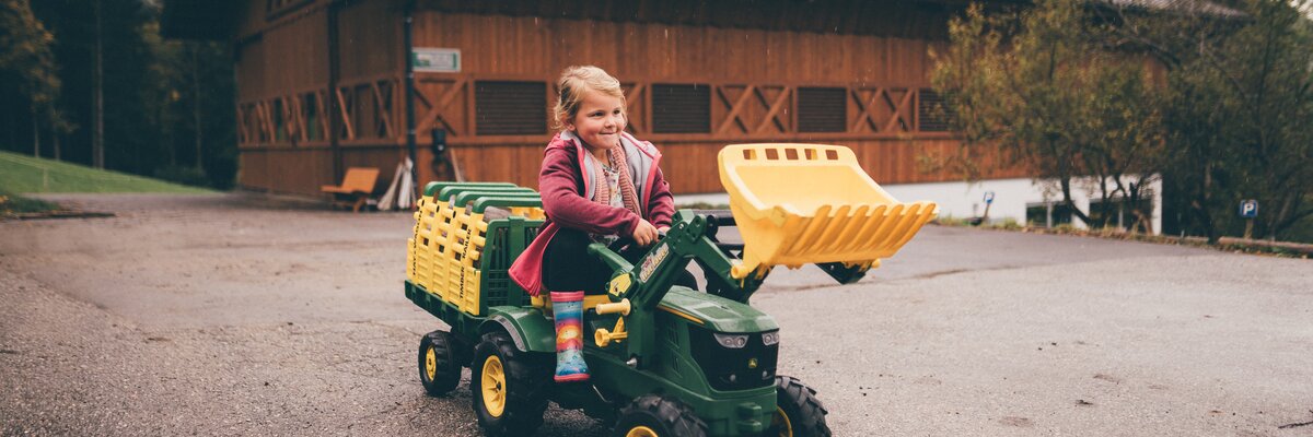 Mädchen sitzt am Trettraktor | © Urlaub am Bauernhof / Daniel Gollner