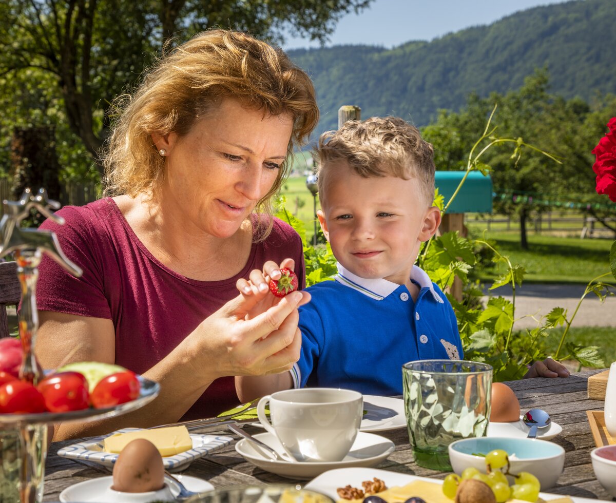 Mutter mit Kind beim Frühstück im Freien am Kinderferienhof Ederbauer am Irrsee | © Urlaub am Bauernhof Österreich / Bernd Suppan