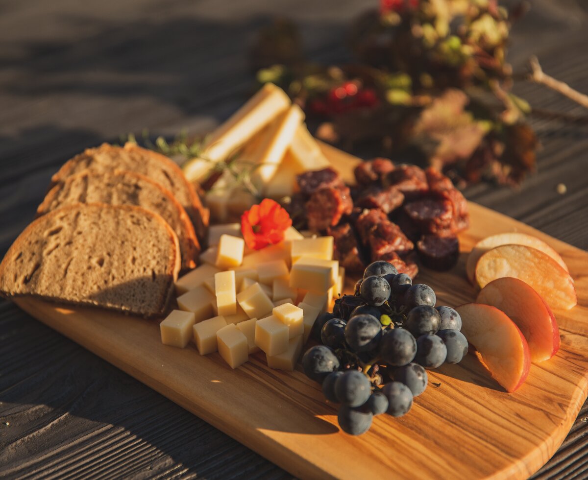 Brettljause mit Brot, Käse, Weintrauben und Apfelscheiben auf dem Holztisch | © Urlaub am Bauernhof in Österreich / Pascal Baronit