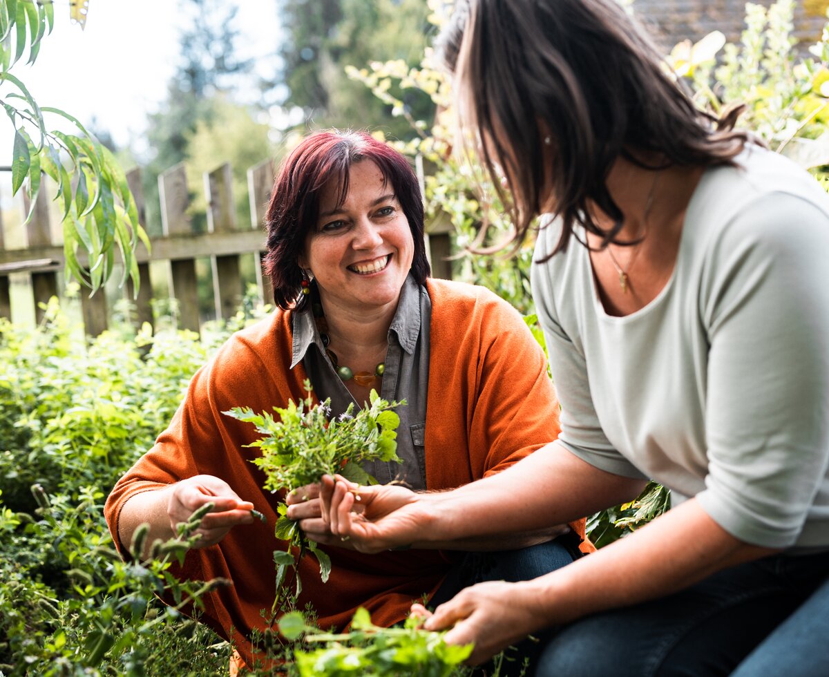 zwei Frauen pflücken Kräuter im Kräutergarten | © Urlaub am Bauernhof / Punkt und Komma