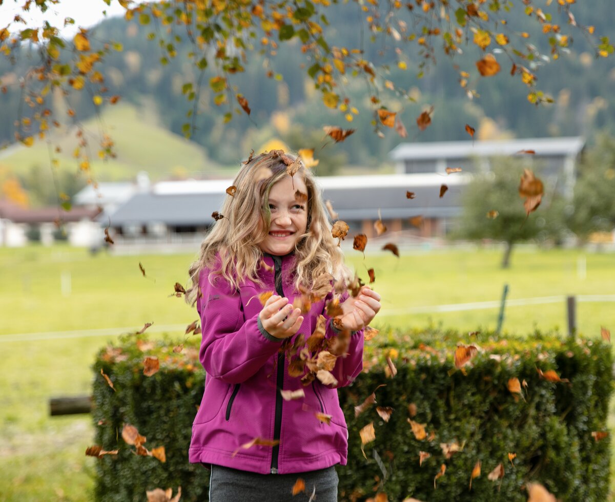 Mädchen mit Herbstlaub | © Urlaub am Bauernhof / Punkt und Komma