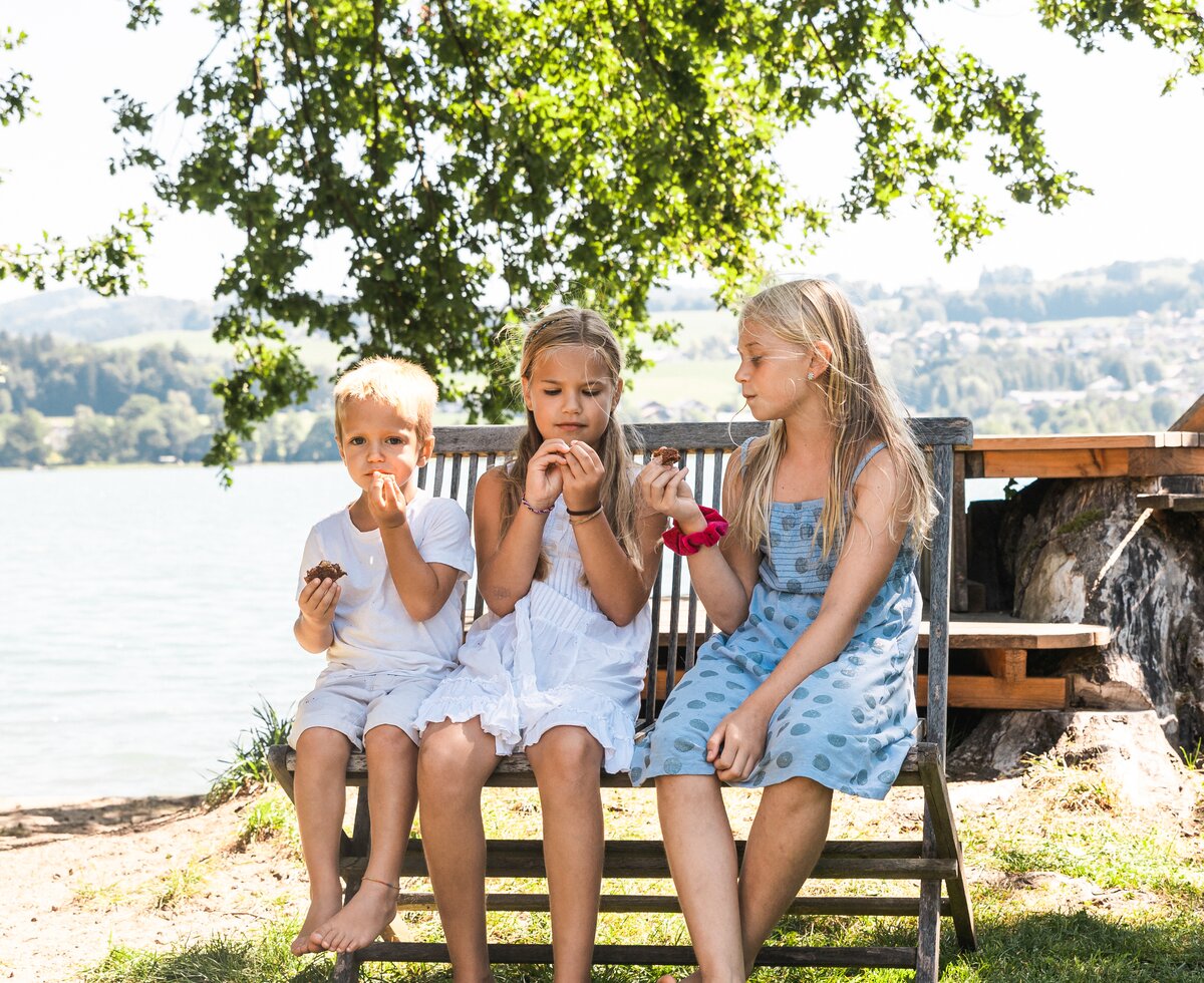 drei kinder sitzen auf einer Bank und essen | © Urlaub am Bauernhof / Punkt und Komma