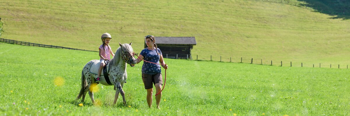 Mädchen reitet über eine Wiese | © Urlaub am Bauernhof / Punkt & Komma