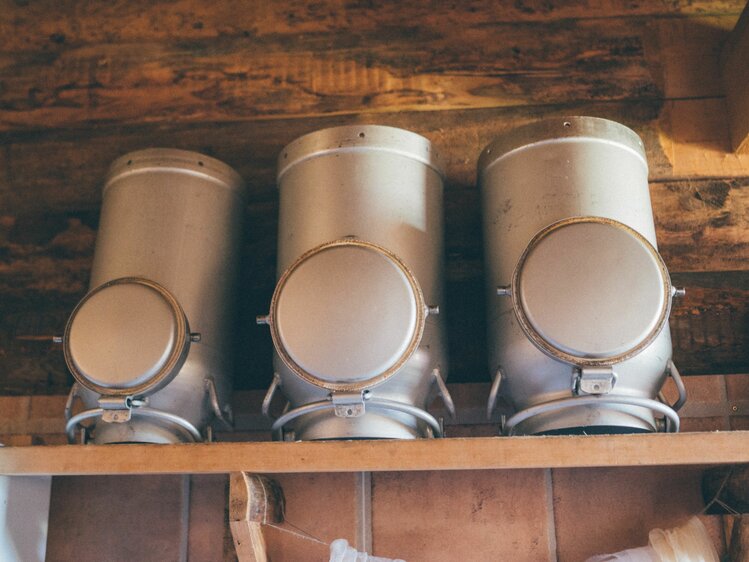 Three milk cans stand on a shelf in the alpine hut of the Grußberggut in Bad Hofgastein | © Farmholidays in SalzburgerLand / Daniel Gollner