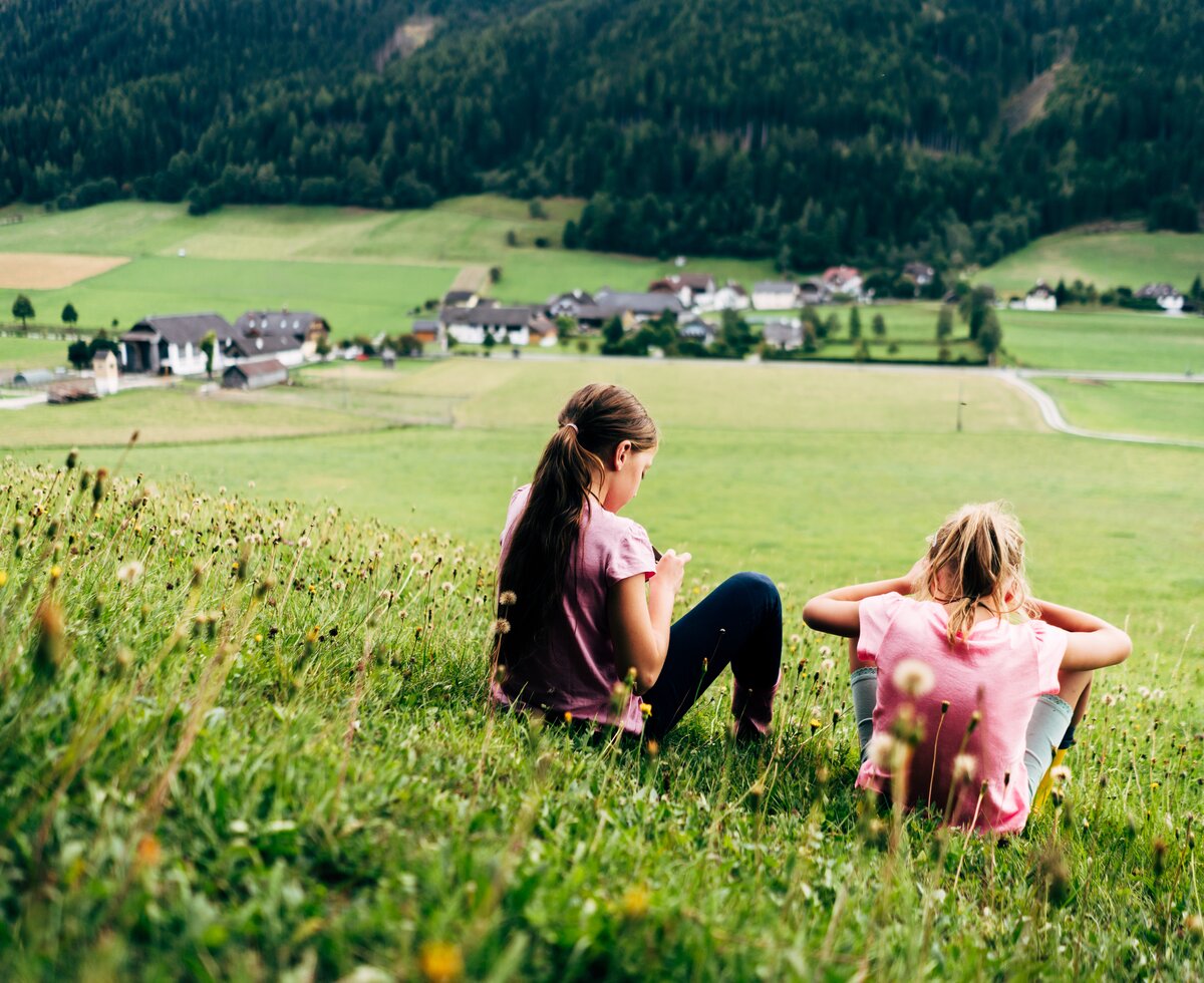 Zwei Mädchen sitzen in der Wiese | © Urlaub am Bauernhof im SalzburgerLand / Daniel Gollner