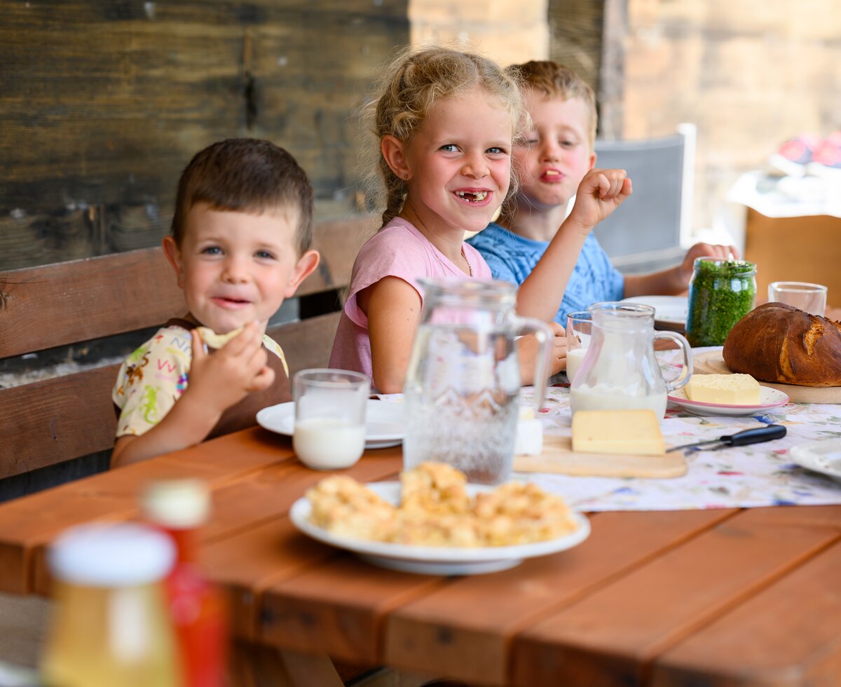 A girl and two boys eating a snack on the terrace, Pausshof in Kleinarl, Salzburger Land | © Urlaub am Bauernhof / punkt&komma