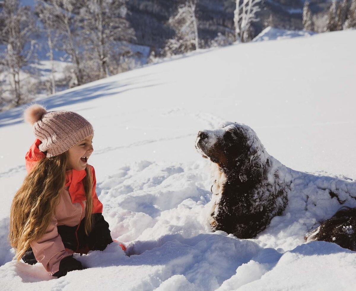 Mädchen spielt mit Hund im Schnee am Proneben Gut in Mühlbach am Hochkönig | © Urlaub am Bauernhof / Punkt & Komma