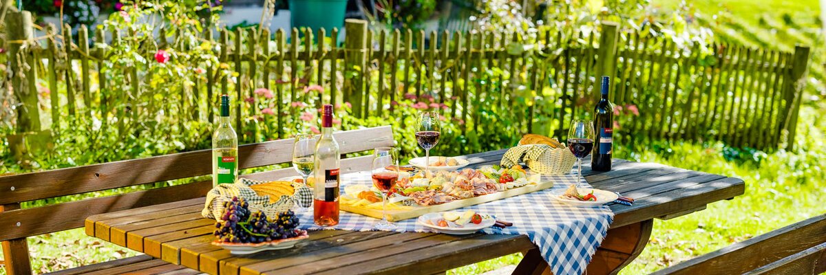 Brettljause mit Wein im Buschenschank im Freien ohne Menschen, Süd-West-Steiermark, Steiermark | © Urlaub am Bauernhof Steiermark / Wolfgang Spekner