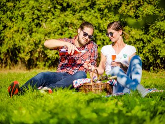 Ein paar sitzt im Weingarten beim Picknick und schenkt sich Schilcherfrizzante ein, Süd-West-Steiermark, Steiermark | © Urlaub am Bauernhof Steiermark / Wolfgang Spekner