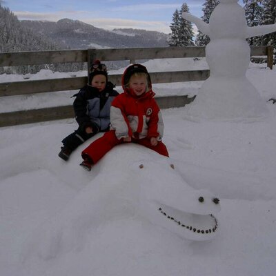 Children on the snow crocodile in front of the cabin