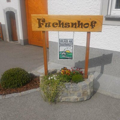 Wooden welcome sign with Fuchsnhof and farm holidays.